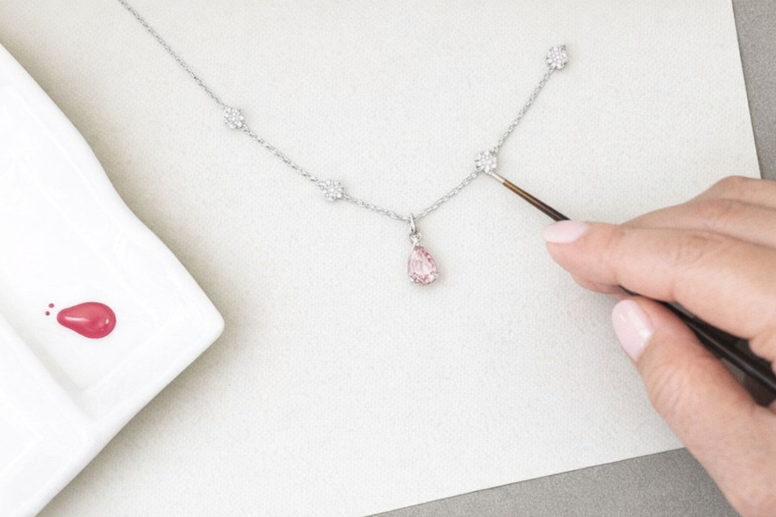 En person arbetar med ett halsband med en rosa diamant.